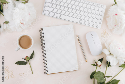 Feminine workspace with blank open notepad and cup of coffee milk, keyboard, stylish office writing supplies and on a pastel teble