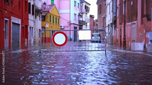 Metal fence with no-entry road sign stands among flood water