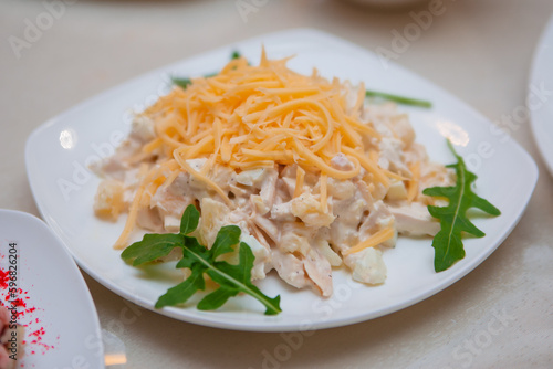 Meat salad with cheese. Chicken food on a white plate. Dish in a restaurant