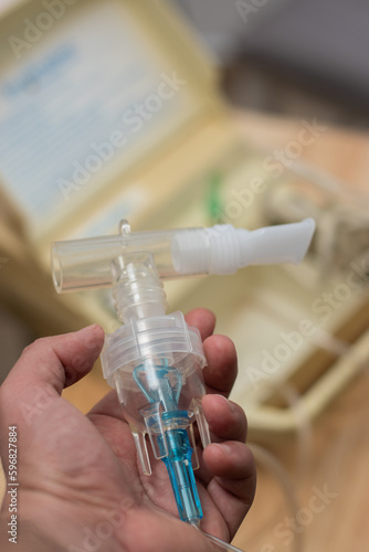 Vertical view of hand holding a nebulizer steam tube with the vaporizer in the background with copy space