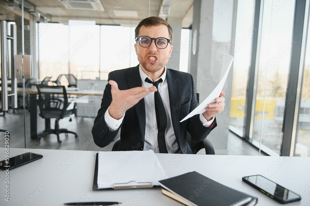 Angry senior businessman sitting at his desk and screaming Angry senior businessman sitting at his desk and screaming
