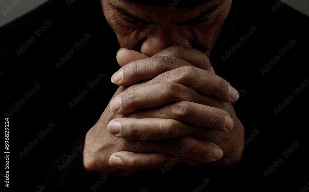 Fototapeta premium man praying to god with hands together Caribbean man praying with black background stock photos stock photo 