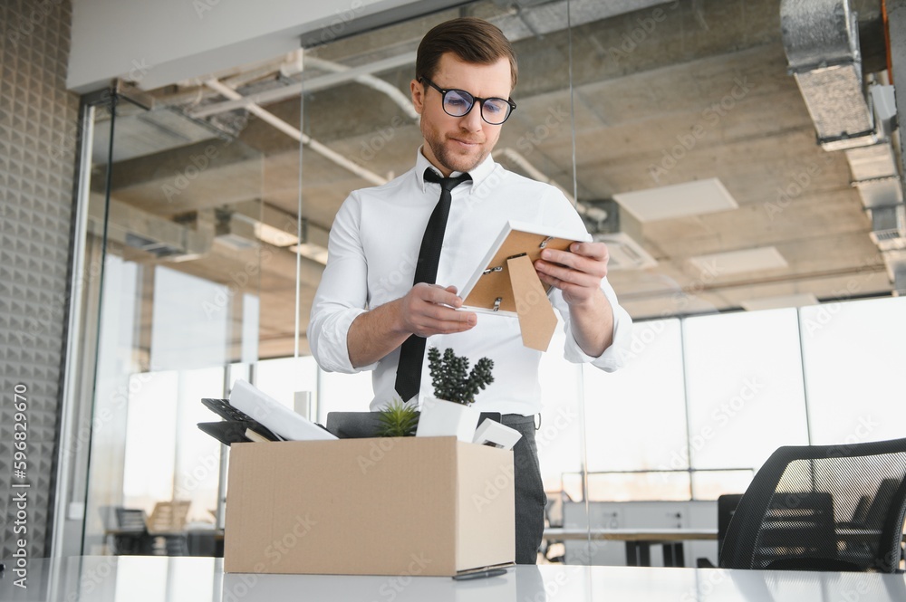 Fired young man packing his stuff in office Fired young man packing his stuff in office