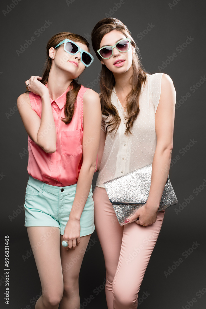 Two peas in a retro pod. Studio shot of two attractive young women dressed up in 60s wear against a dark background.