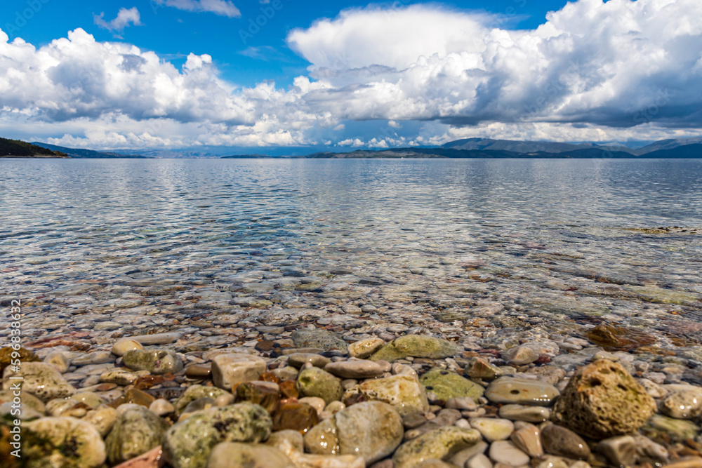 Obraz premium A beautiful landscape of the coast of the island of Corfu in the Ionian Sea of the Mediterranean in Greece. Pure blue clear water washes over the shores of the Greek island.