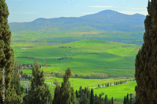 Panorama of the Tuscan green hills against the blue sky from the streets of the medieval small town of Pienza on an April afternoon.