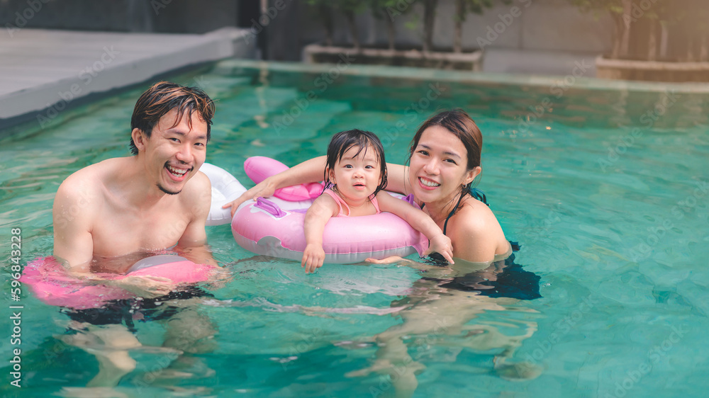 Asian little baby girl swimming and wear rubber ring in pool, Mother and father holding daughter for safety support, Living lifestyle family indoors concept. Asian little baby girl swimming and wear rubber ring in pool, Mother and father holding daughter for safety support, Living lifestyle family indoors concept.