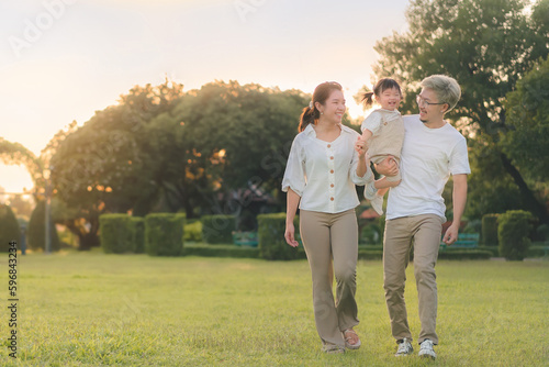 Asian father and mother walking with daughter in park, Parents hold the baby's , Happy family in the park evening light. Happy family concept.