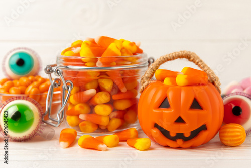 Fototapeta Naklejka Na Ścianę i Meble -  Halloween candy on a white background. coffee corn and sazar skull.Halloween holiday background with jack o lantern pumpkin, candy corn and decorations.Top view.Flat lay. Place for text.