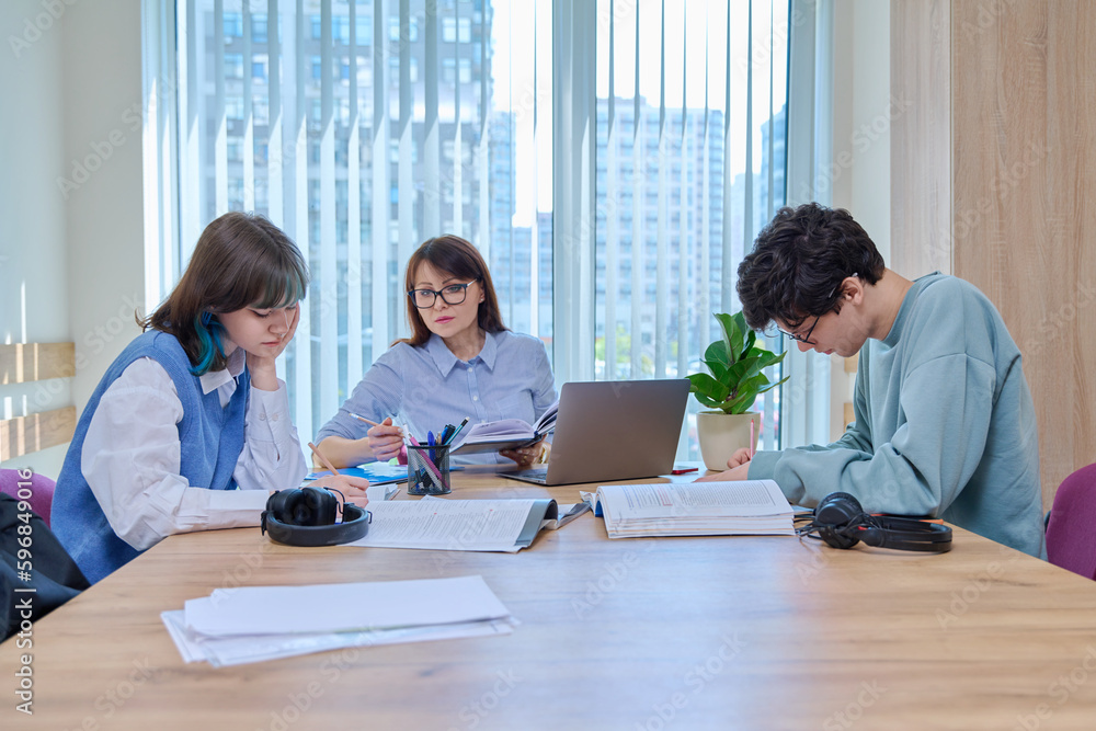 College students with teacher sitting at desk in classroom studying languages, sciences College students with teacher sitting at desk in classroom studying languages, sciences