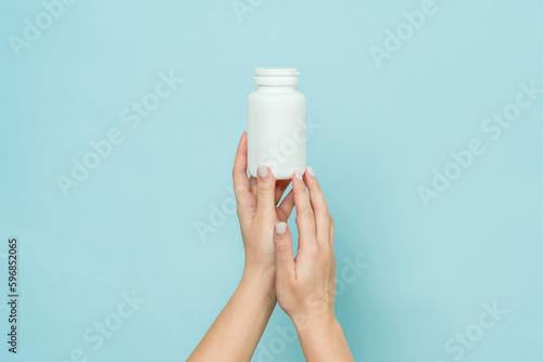 White plastic tube in female hand. Bottle for pill, capsule or supplement. Product branding mockup