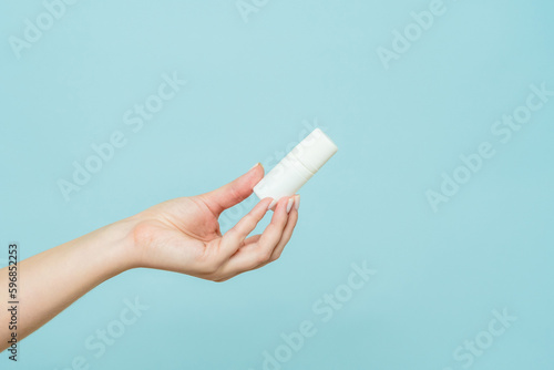 Bottle of nasal spray or eye drops in a female hand. Copy space