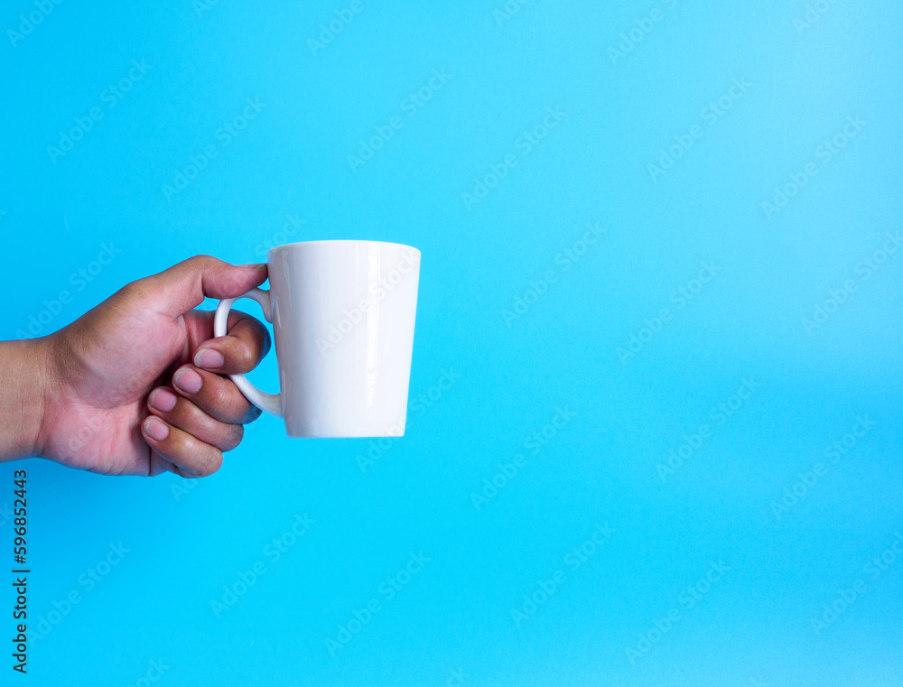 Obraz premium Man hand holding a white coffee cup, filled with hot black coffee(americano), no sugar no milk, ready to drink, refreshing. aroma awake fresh to work placed on a blue isolated background