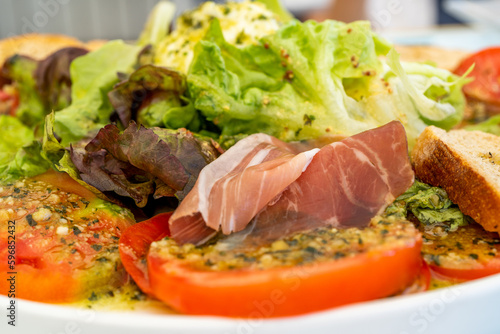 Whole buffalo mozzarella with pesto sauce, salad leaves, tomatoes and spanish sausage