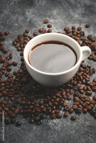 front view of brown coffee seeds with cup of coffee on dark background textured grain group