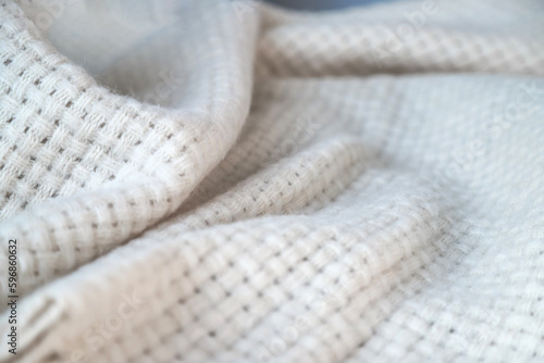 Texture of a wavy surface of a warm and cozy white woven blanket as a background