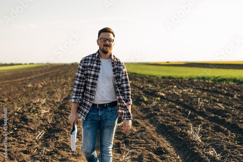 Front view of a businessman farmer walking in the field.