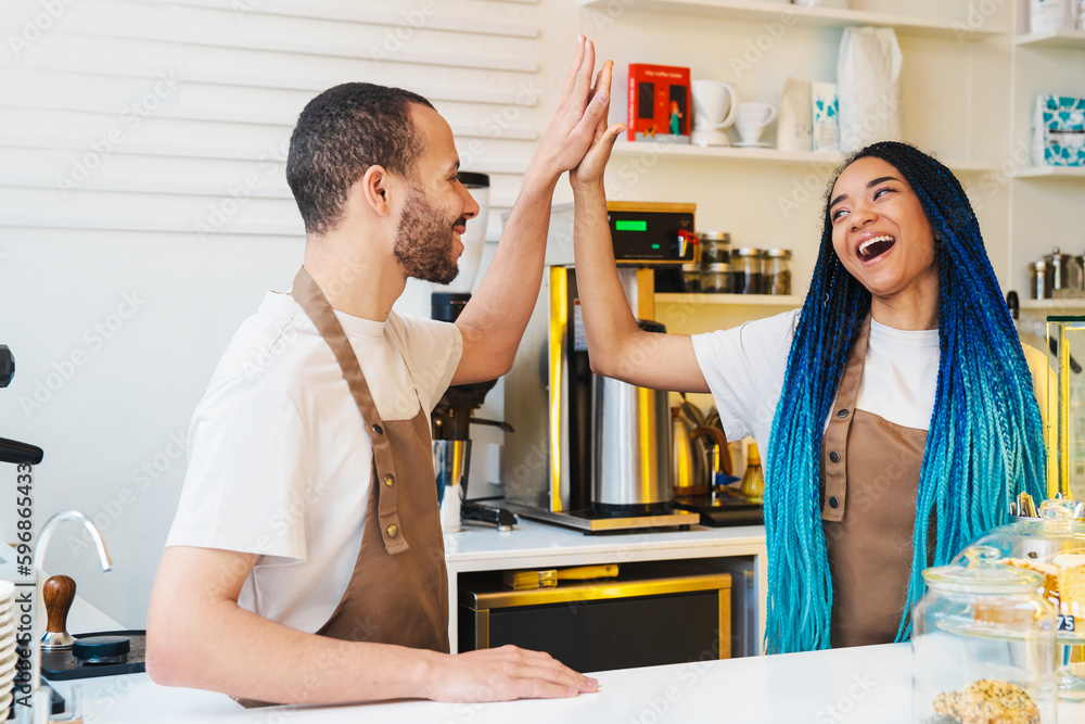 Couple barista raising arm pose for success at work in cafe