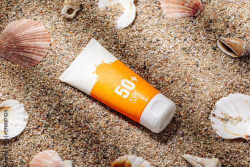 Foto Orange tube of sunscreen on sandy beach top view