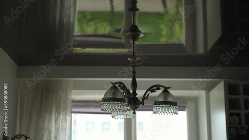 Wallpaper Mural Vintage chandelier with three arms hangs from glossy stretch ceiling in small empty room in sleeping area. Cloudy day and tulle on one side, grass reflection on ceiling under window. Torontodigital.ca