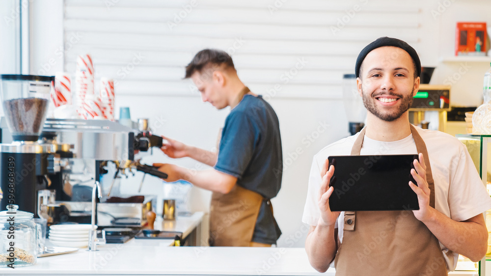 Fototapeta premium Smiling male barista showing digital tablet screen, copy space