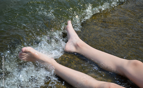 female feet on a stone are washed by sea water. sunbathing and washing feet in salt water while resting and relaxing. summer vacation