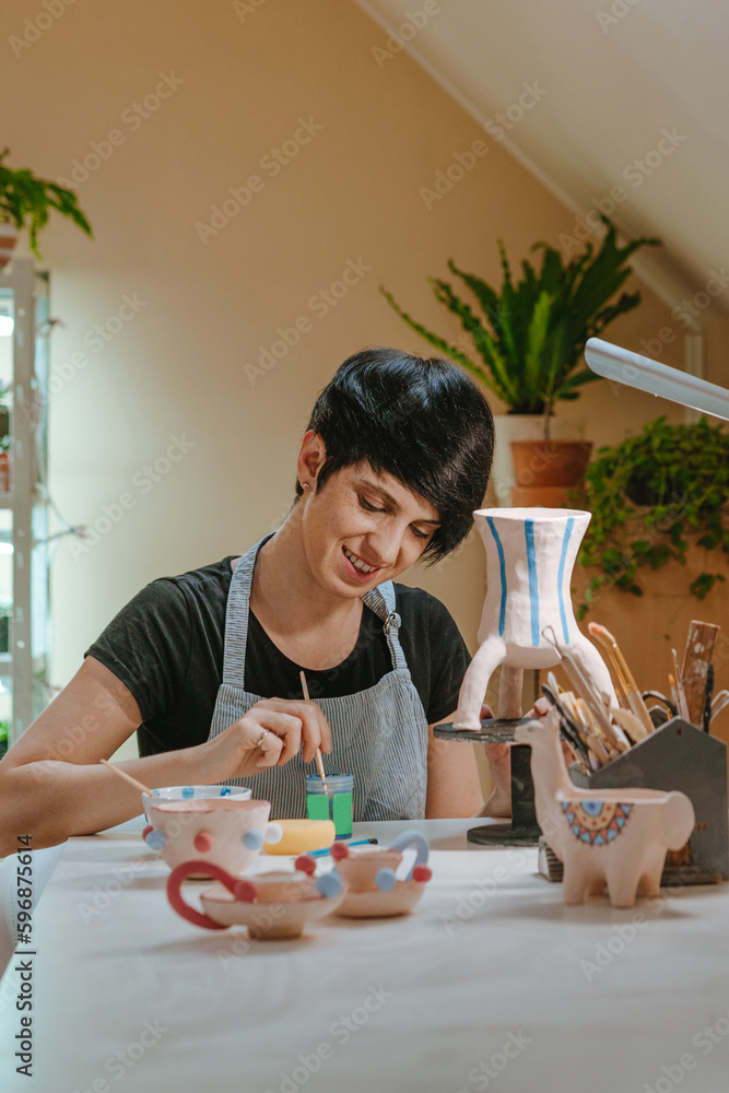 Young woman artisan painting a vase at workshop Young woman artisan painting a vase at workshop