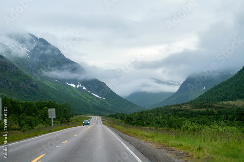 Asphalt road in a deep valley between mountains in the clouds in the north of Europe in Norway