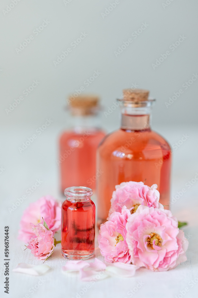 Concept of perfume with pure natural organic rose ingredient, essential oils. Glass bottles with flower herbal extract and elixir. Perfumery cosmetic toilet water fragrance, cream, skin care product Concept of perfume with pure natural organic rose ingredient, essential oils. Glass bottles with flower herbal extract and elixir. Perfumery cosmetic toilet water fragrance, cream, skin care product