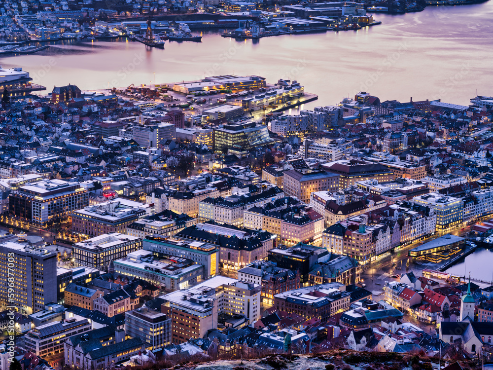 Aerial shot of Bergen city buildings and streets lit up after sunset, Norway