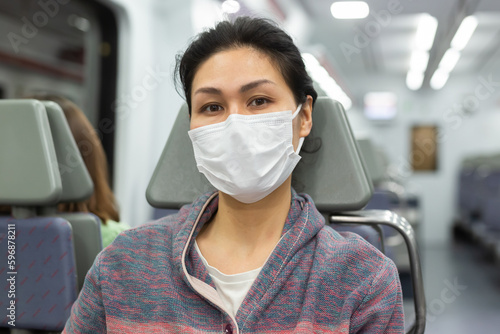 Asian woman in protective mask sitting in subway train