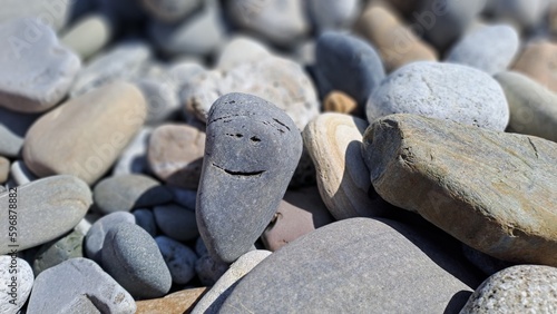 Smiling stone among other coastal stones
