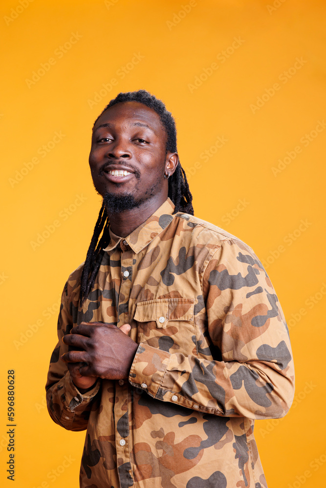 Smiling cheerful man smiling at camera while posing happy in studio with yellow background, having positive expression. Confident beautiful african american model with stylish hairstyle Smiling cheerful man smiling at camera while posing happy in studio with yellow background, having positive expression. Confident beautiful african american model with stylish hairstyle
