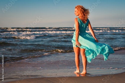 Beautiful blonde woman on a sandy beach. Photo taken on the Baltic Sea in Leba, Poland. Photo with a shallow depth of field with blurred background.
