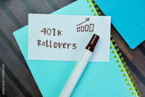 Concept of 401k Rollovers write on sticky notes isolated on Wooden Table.
