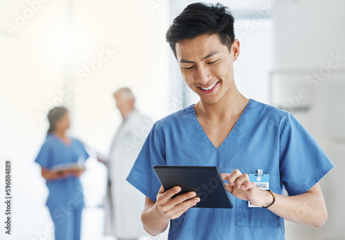 Getting loads more done in digital format. Shot of a young doctor using a digital tablet in a hospital.