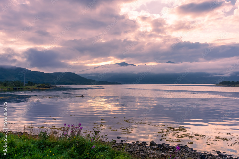 Fototapeta premium Spectacular reflection of the mountains on a lake with mist under the midnight sun, fairy tale atmosphere in the Vesteralen Islands, Norway