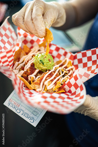 Fényképezés Close-up food worker's gloved hands serving Loaded Nachos with Salsa, Guacamole