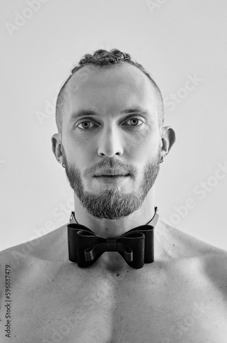 Monochrome portrait of handsome caucasian athletic young man topless in leather bow tie. Fitness, bodybilding  photo