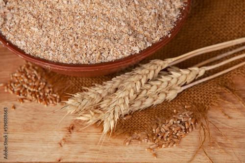 Obraz na płótnie Wheat bran in a clay bowl and ears of wheat on a wooden background. Healthy food background. Food and baking ingredient. w salonie