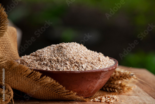 Obraz na płótnie Wheat bran in a clay bowl and ears of wheat on a burlap background. Healthy food background. Food and baking ingredient. w salonie