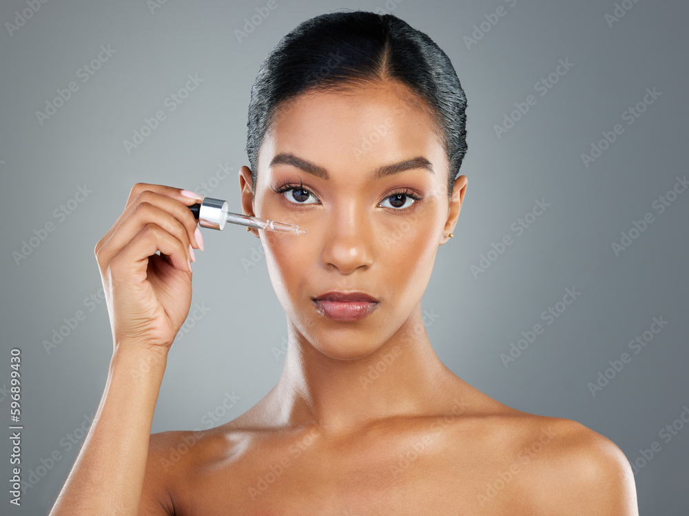 Lets jump on skincare. Shot of a beautiful young woman applying a face serum with a dropper.