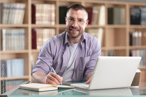 Happy professional young business man on library background