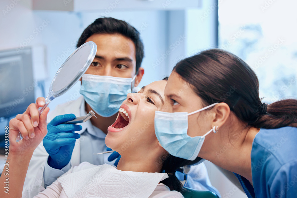 What would you like done. Shot of a young woman checking her results in the dentists office.