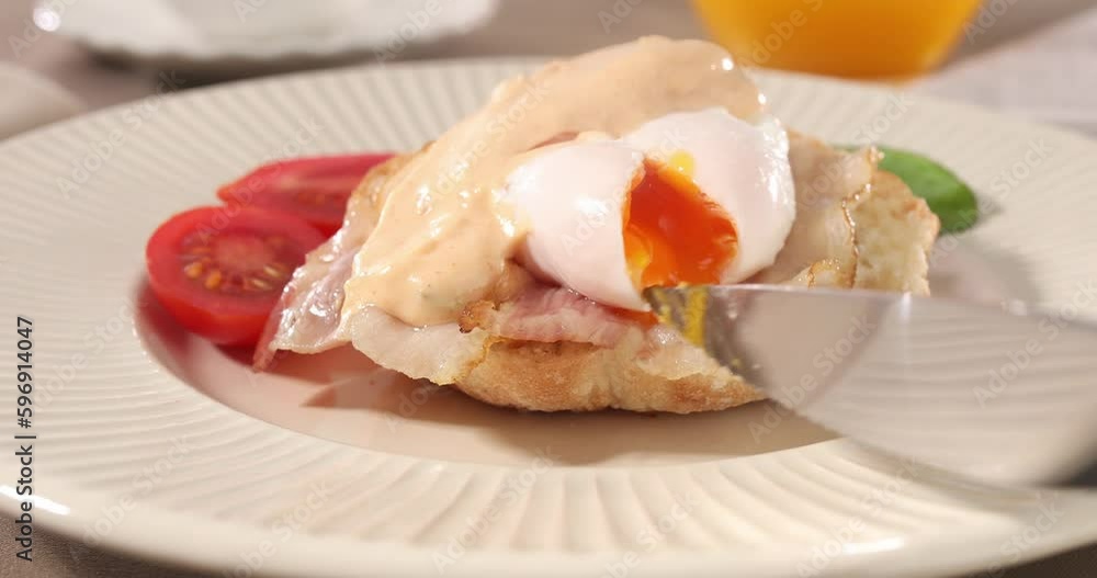 cutting poached egg with bacon on a plate. boiled egg on bread with sauce. delicious breakfast with vegetables. serving food on a sunny day. cutting poached egg with bacon on a plate. boiled egg on bread with sauce. delicious breakfast with vegetables. serving food on a sunny day.