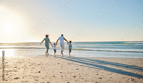 Lets go splish and splash. Rearview shot of a happy family walking towards the sea.