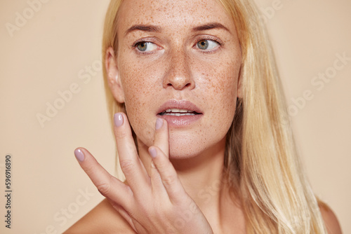 Tablou pe pânză Woman with freckles touching her lip with a finger