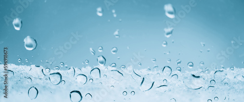 Minimal light backdrop with rain droplets on white glass. Light wet window with rainy drops closeup in blue light. Blurry minimalist monochrome background of window glass with raindrops close up.