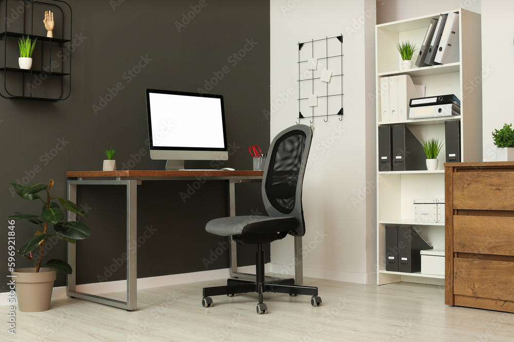 Fototapeta premium Stylish office interior with comfortable chair, desk and computer