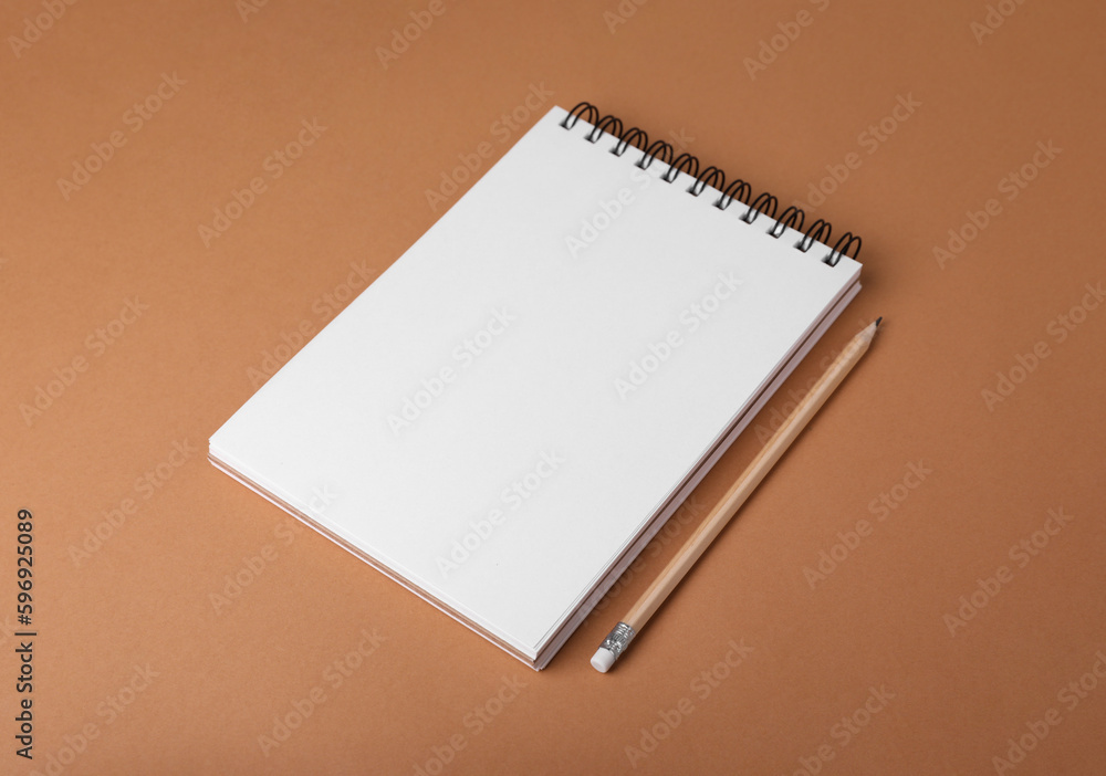 Open notebook and pencil on light brown background Open notebook and pencil on light brown background